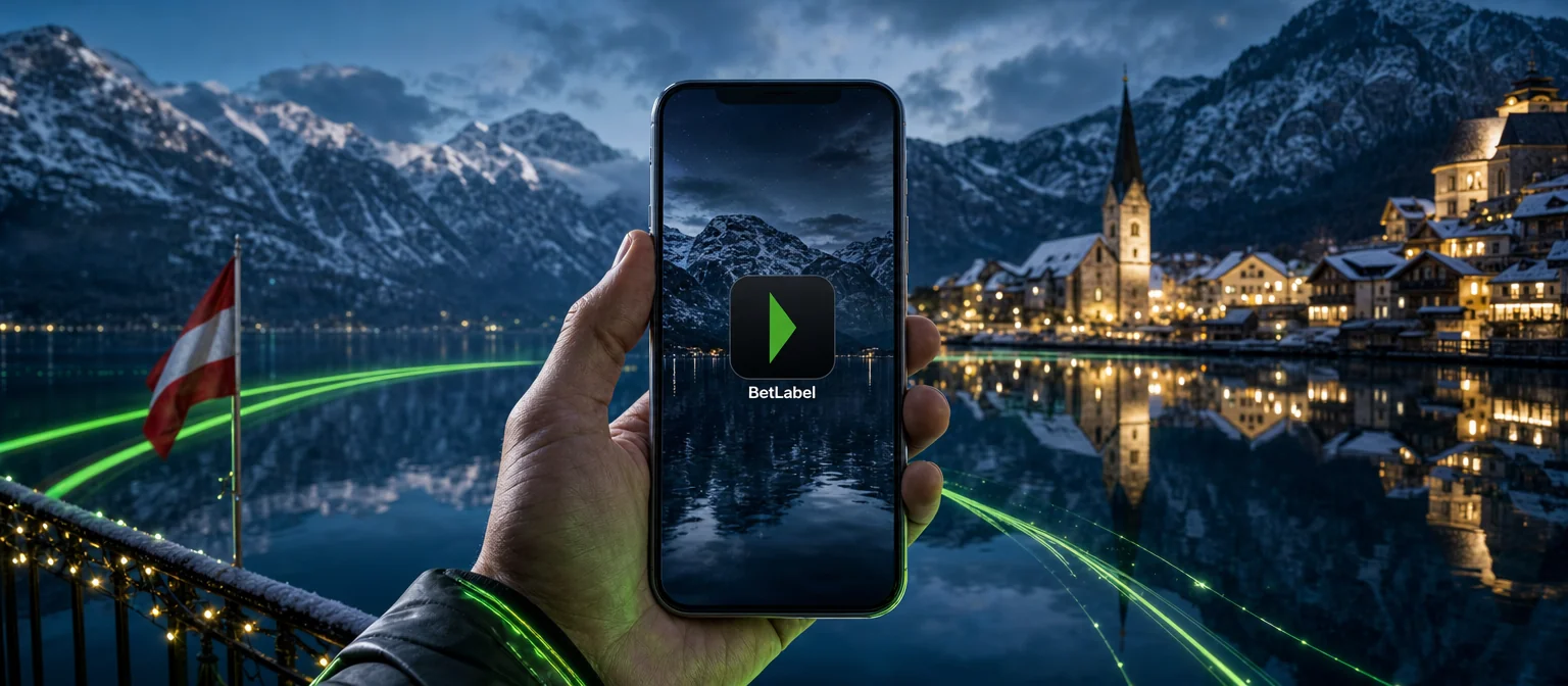 Handy mit dem BetLabel-Symbol auf dem Startbildschirm, dahinter der Hallstätter See zur blauen Stunde